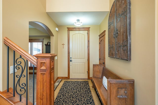 entrance foyer featuring arched walkways, stairway, and baseboards