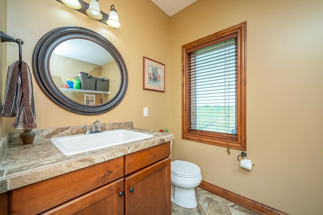 bathroom with vanity, toilet, and baseboards