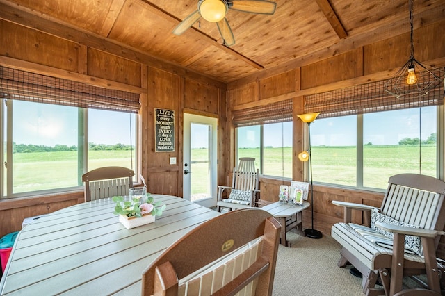 dining room with carpet floors, wood ceiling, wood walls, and a ceiling fan