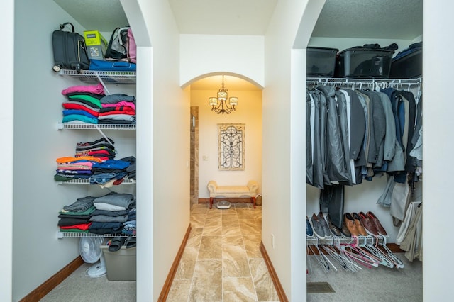 spacious closet featuring arched walkways and a chandelier