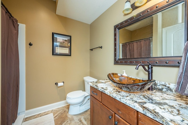 bathroom featuring toilet, vanity, and baseboards