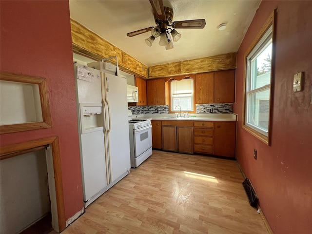 kitchen with light countertops, brown cabinets, white appliances, a ceiling fan, and a sink