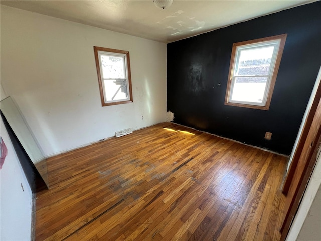 empty room with hardwood / wood-style floors and visible vents