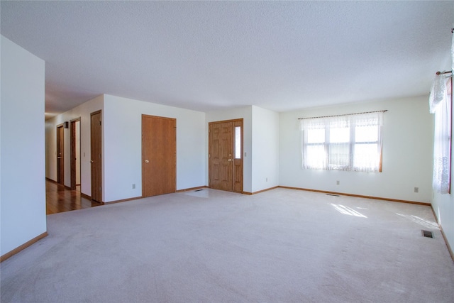 unfurnished room featuring visible vents, baseboards, light colored carpet, and a textured ceiling