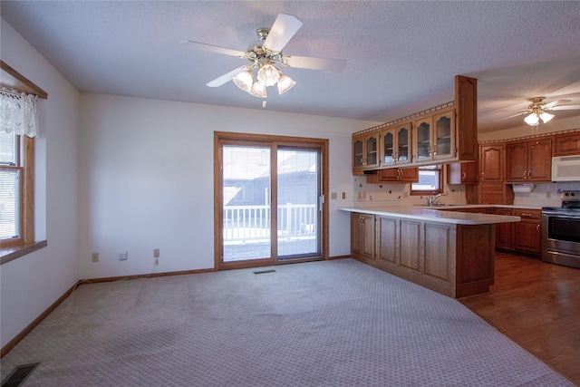 kitchen featuring visible vents, electric stove, a peninsula, white microwave, and ceiling fan