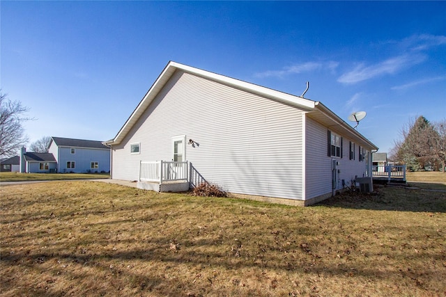 view of side of property featuring cooling unit and a yard