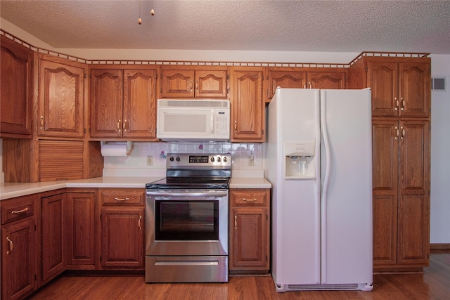 kitchen with white appliances, wood finished floors, and light countertops