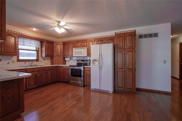 kitchen with a sink, visible vents, white appliances, and brown cabinetry