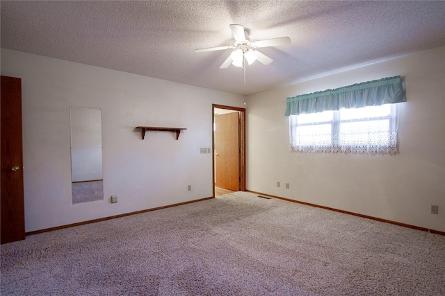 unfurnished room with carpet, visible vents, a ceiling fan, baseboards, and a textured ceiling