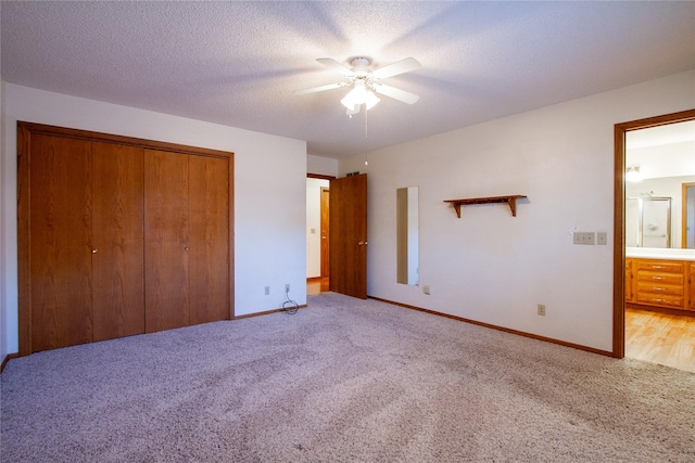 unfurnished bedroom featuring a textured ceiling, ceiling fan, a closet, and light carpet