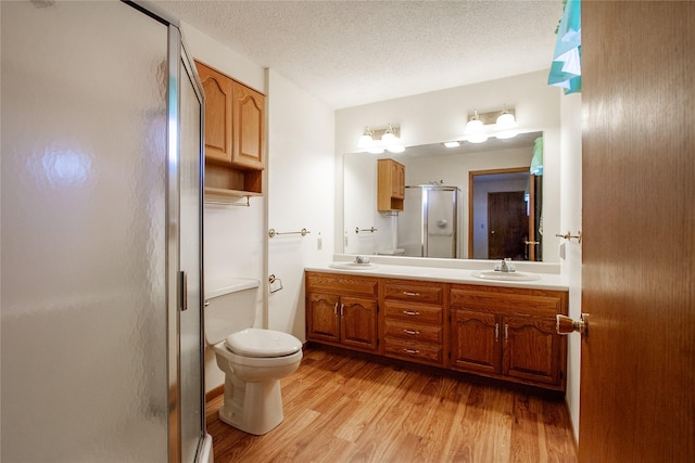 bathroom with a textured ceiling, a shower stall, wood finished floors, and a sink