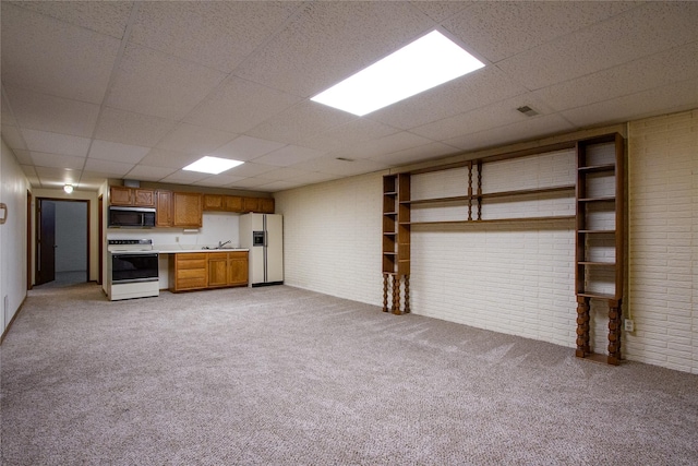 kitchen with brick wall, light countertops, light carpet, brown cabinetry, and white appliances