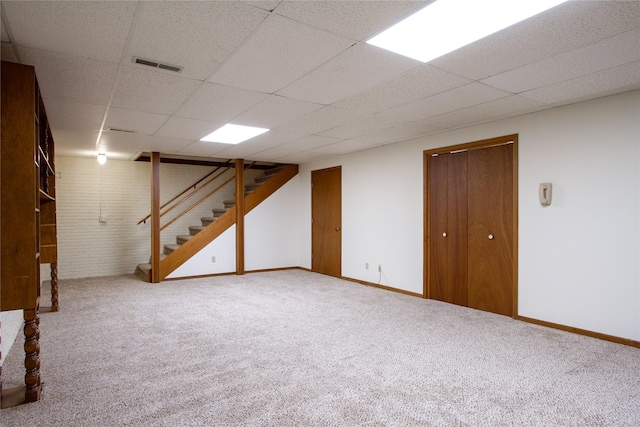 finished basement with visible vents, carpet flooring, stairs, and a drop ceiling