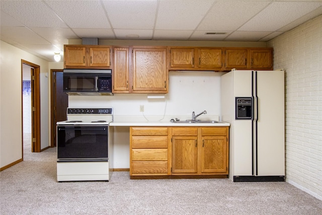 kitchen featuring light carpet, a sink, a drop ceiling, white appliances, and light countertops