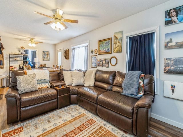 living area with wood finished floors, a ceiling fan, baseboards, and a textured ceiling