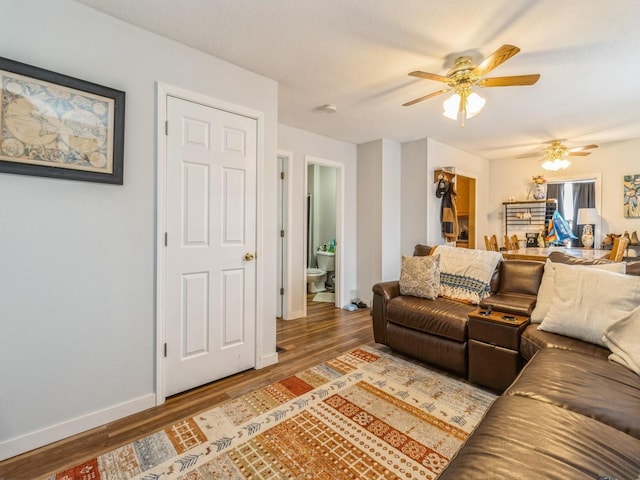 living room with baseboards, wood finished floors, and ceiling fan