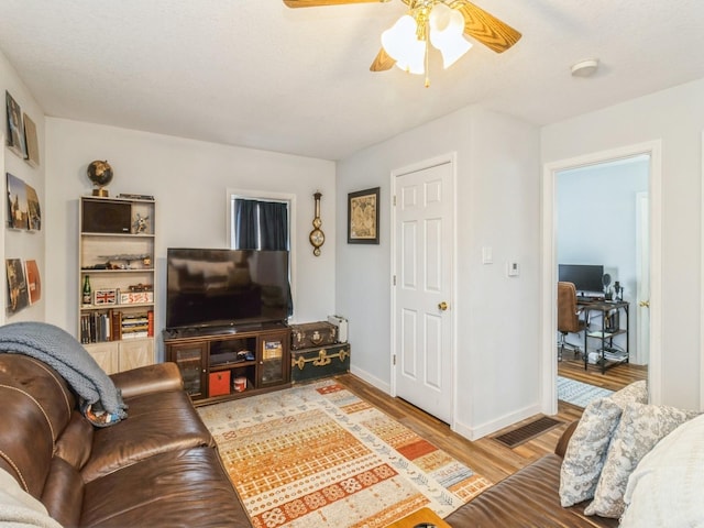 living area featuring baseboards, visible vents, light wood-type flooring, and ceiling fan