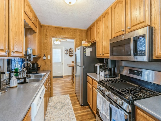 kitchen featuring decorative backsplash, appliances with stainless steel finishes, light wood-style floors, a textured ceiling, and a sink