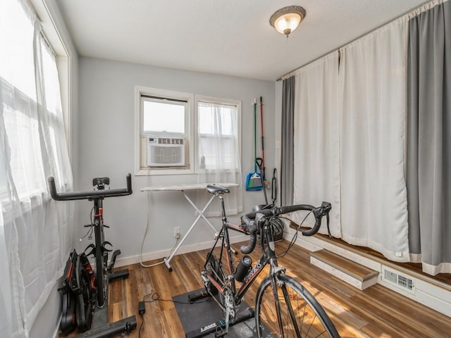 workout area with visible vents, baseboards, and wood finished floors