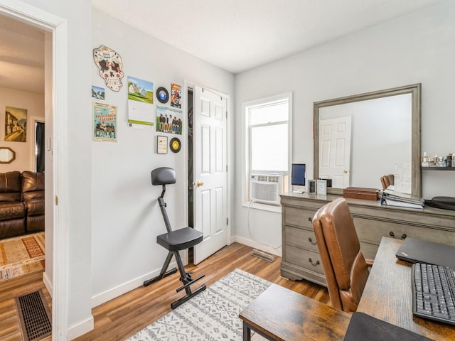 office with light wood-type flooring, baseboards, visible vents, and cooling unit