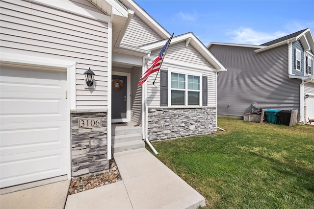 view of exterior entry featuring a garage, a yard, and stone siding