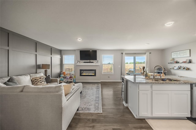 living room featuring dark wood-style floors, a glass covered fireplace, recessed lighting, and baseboards