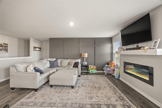 living room with a glass covered fireplace, wood finished floors, and baseboards