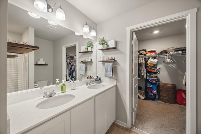 full bath featuring double vanity, visible vents, toilet, and a sink