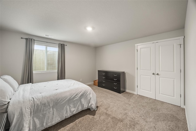 bedroom featuring a closet, visible vents, carpet flooring, and baseboards