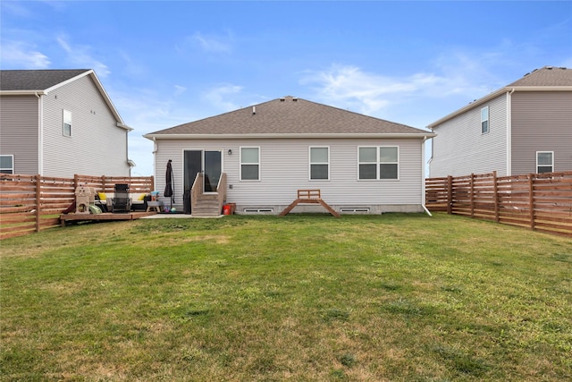 back of house with entry steps, a lawn, a fenced backyard, and roof with shingles