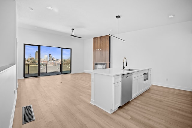 kitchen featuring visible vents, a sink, open floor plan, light wood finished floors, and dishwasher