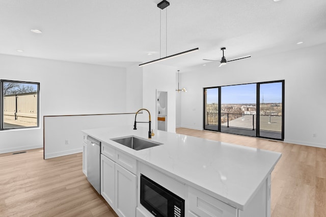 kitchen with a sink, open floor plan, black microwave, dishwasher, and ceiling fan