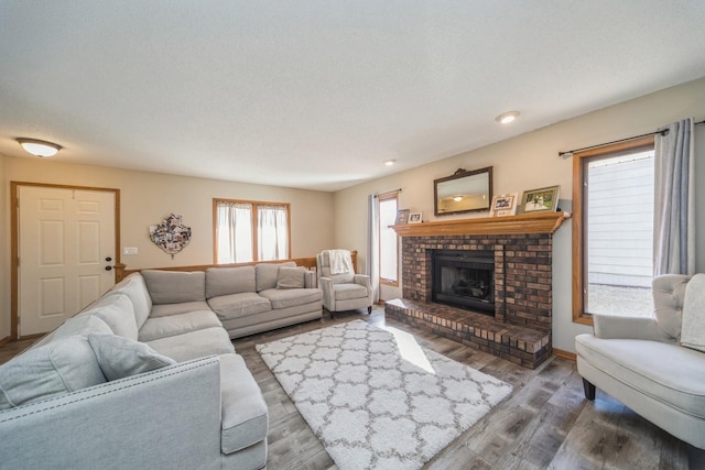 living room featuring a fireplace, wood finished floors, baseboards, and a textured ceiling