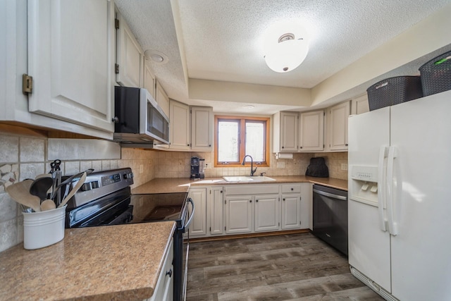 kitchen with light countertops, decorative backsplash, appliances with stainless steel finishes, dark wood-style floors, and a sink