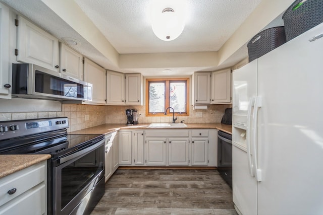 kitchen featuring a sink, decorative backsplash, light countertops, dark wood-type flooring, and stainless steel appliances