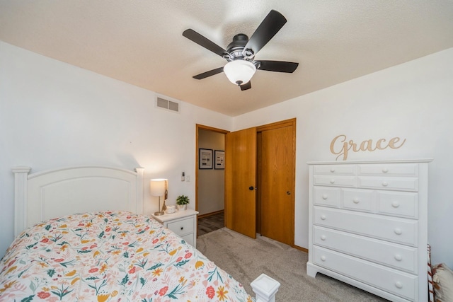 bedroom featuring visible vents, light colored carpet, a closet, and a ceiling fan