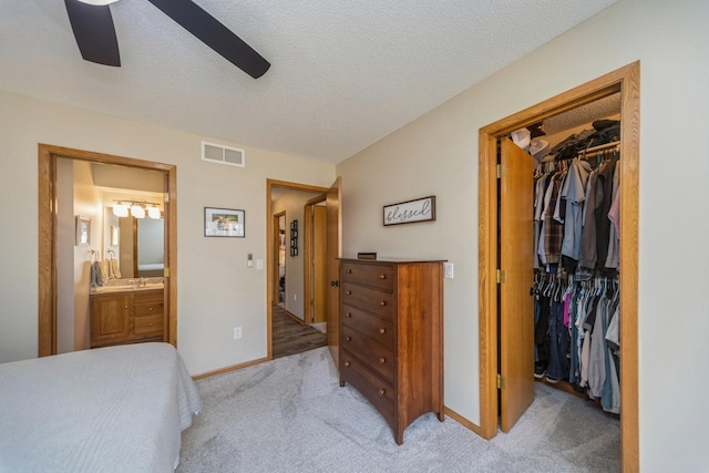 bedroom with visible vents, a textured ceiling, a closet, light colored carpet, and a spacious closet