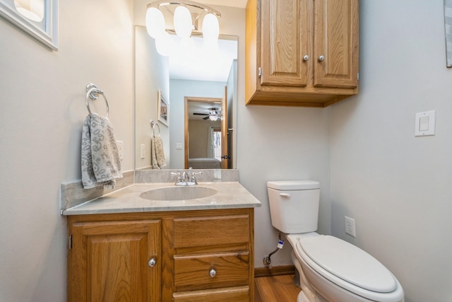 half bathroom with vanity, toilet, and a ceiling fan