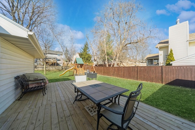 deck with a fenced backyard, a playground, a yard, a grill, and outdoor dining area