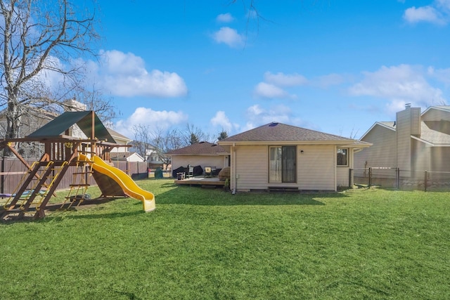 exterior space with a wooden deck, a playground, a yard, and fence