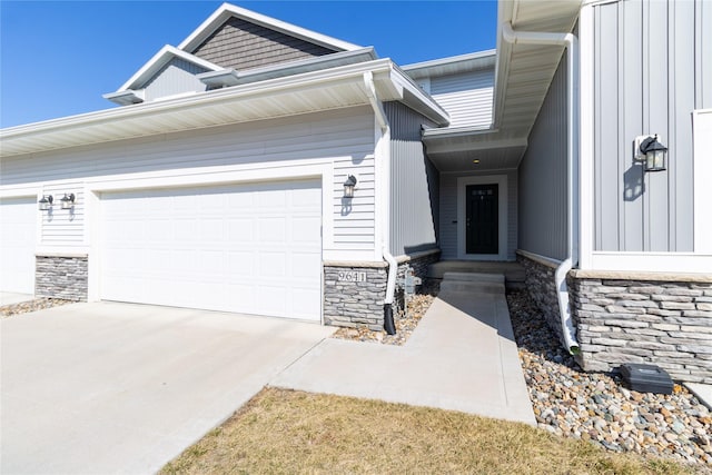 view of front of property featuring a garage, stone siding, board and batten siding, and driveway