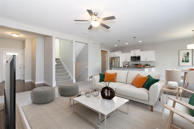 living area featuring baseboards, visible vents, recessed lighting, ceiling fan, and stairs