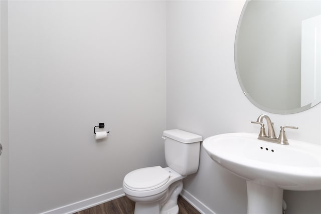 bathroom with a sink, baseboards, toilet, and wood finished floors