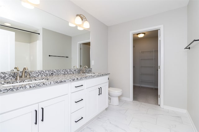 bathroom with a sink, a walk in closet, baseboards, and marble finish floor