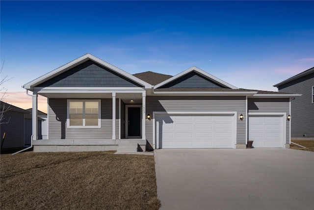 view of front facade with a garage, a porch, and driveway