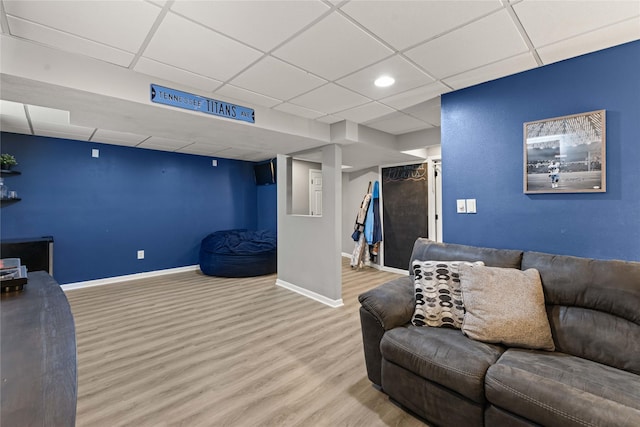 living room featuring baseboards, a paneled ceiling, and wood finished floors