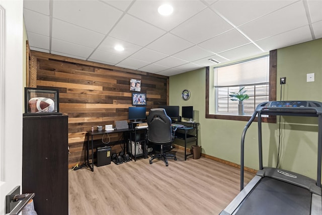 office area with wood walls, a paneled ceiling, baseboards, and wood finished floors