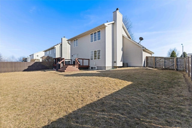 back of house featuring a chimney, a yard, a wooden deck, and a fenced backyard