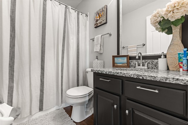 full bath featuring a shower with shower curtain, toilet, and vanity