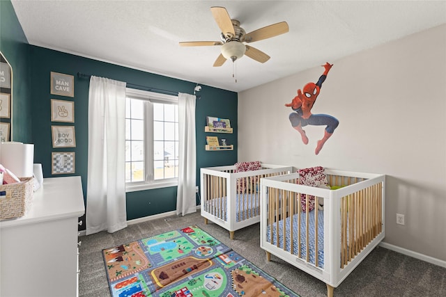 carpeted bedroom with ceiling fan, baseboards, and a nursery area